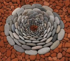 a large flower made out of rocks on top of a rock ground with the center surrounded by smaller rocks