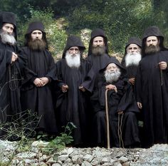 a group of men with long beards standing next to each other in black robes