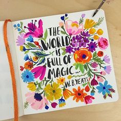 an open notebook with colorful flowers and the words, the world is full of magic