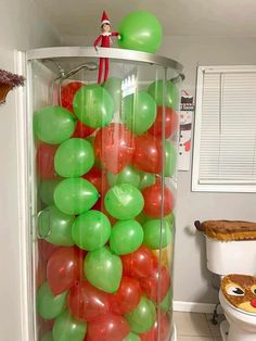 an elf is sitting on top of a tower filled with green, red and white balloons