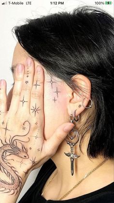 a woman covering her face with both hands and showing tattoos on her upper half body