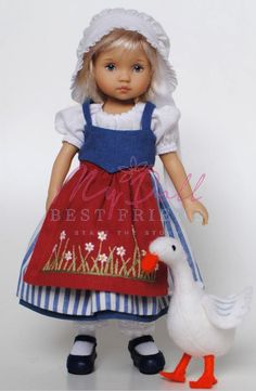 a doll with a duck next to it on a white background in a red and blue dress