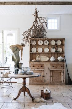 a dining room table with plates on it and a vase hanging from the ceiling above