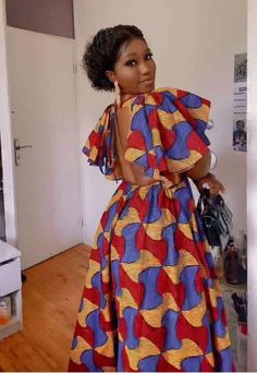 a woman standing in a room wearing a colorful dress