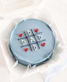 a blue cake decorated with hearts and the words dad written on it in white icing