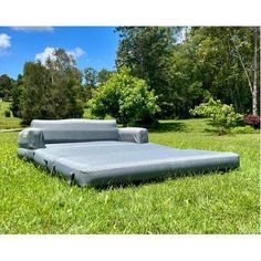 an inflatable bed sitting on top of a green grass covered field next to trees