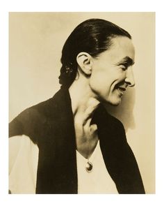 an old black and white photo of a woman with her hand on her neck smiling