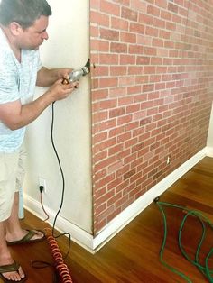 a man using a power drill to fix a brick wall