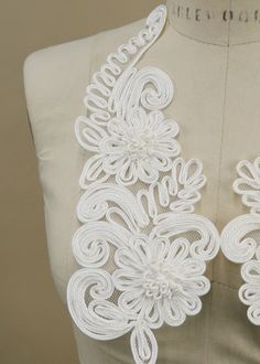 the back of a white dress with flowers on it's chest and neckline