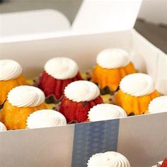 cupcakes with white frosting and strawberries in a box on a table