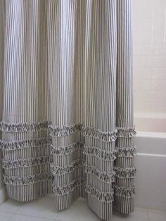 a white bath tub sitting next to a shower curtain with ruffles on it