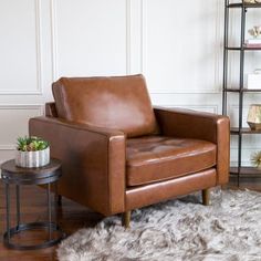 a brown leather chair sitting on top of a wooden floor next to a small table