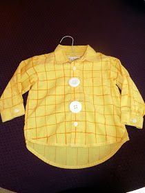 a yellow shirt with buttons on it sitting on top of a black table next to a pair of scissors