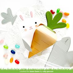 an easter bunny in a carrot shaped paper box surrounded by candy candies and crayons