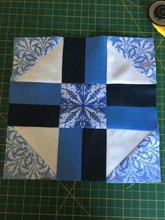 a blue and white patchwork block on a cutting board with scissors next to it