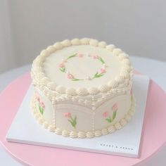 a white cake sitting on top of a pink table