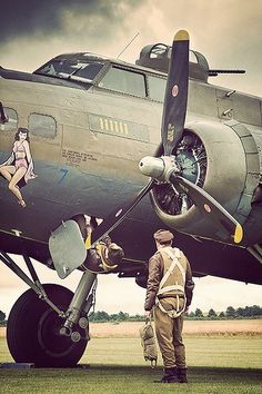 a man standing next to an airplane on top of a field