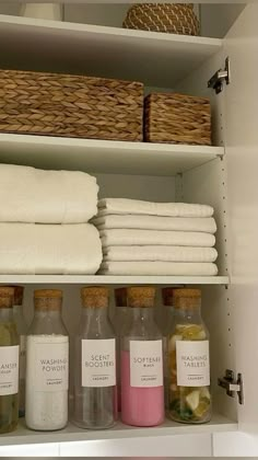 towels, soaps and other items are on shelves in a bathroom cabinet with baskets