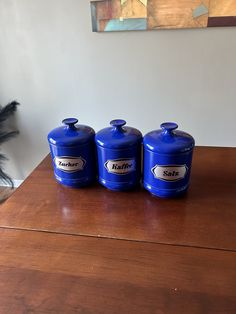 three blue canisters sitting on top of a wooden table