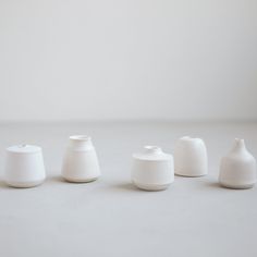 five white vases are lined up in a row