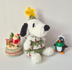 two stuffed animals are sitting next to each other on a white surface, one is wearing a christmas sweater and the other has a penguin