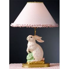 a white rabbit lamp sitting on top of a table next to a pink lampshade