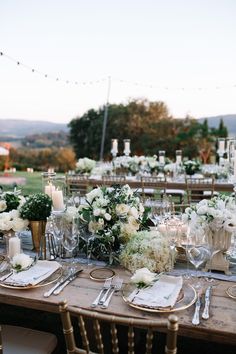 a table set up with white flowers and candles