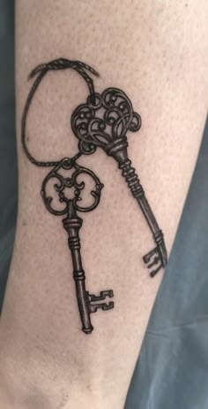 a black and white photo of a key tattoo on the leg