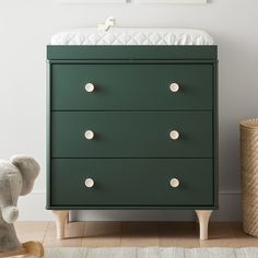 a green dresser with white knobs in a nursery