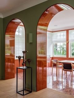 an arched doorway leads to a dining room with green walls and wood trimmings