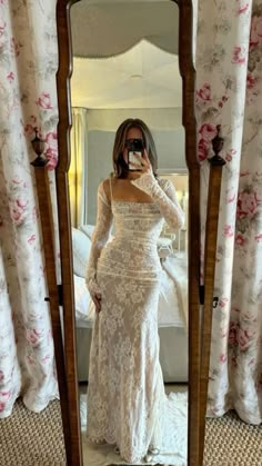 a woman taking a selfie in front of a mirror wearing a white lace dress