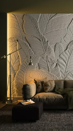 a living room with a couch, lamp and large wall papered design on the wall