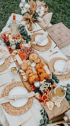 a table set up with plates, bowls and napkins for an outdoor dinner party