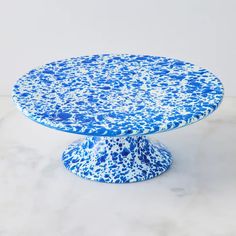 a blue and white cake plate sitting on top of a marble tablecloth covered counter