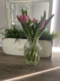 pink tulips are in a clear vase on a table