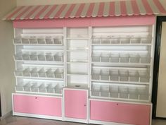 a pink and white display case with lots of bins on it's sides