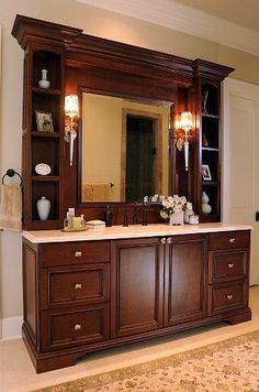 a bathroom with a large mirror, sink and wooden cabinetry in it's center