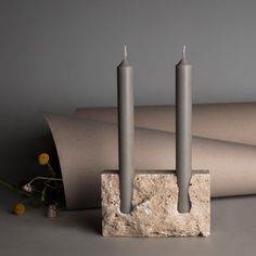 two candles sitting on top of a stone block