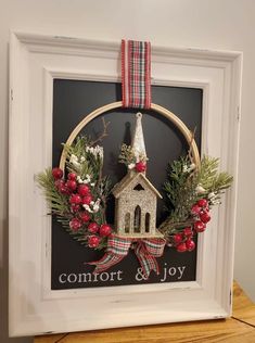 a christmas wreath with a small church on it is hung in front of a blackboard