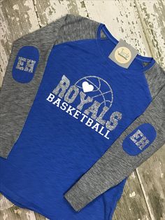 two blue and gray baseball shirts sitting on top of a wooden floor