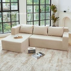 a living room with a couch and book on the floor in front of large windows