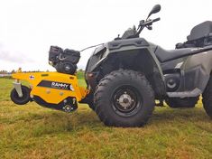 an atv with a trailer attached to it on the grass in front of a field