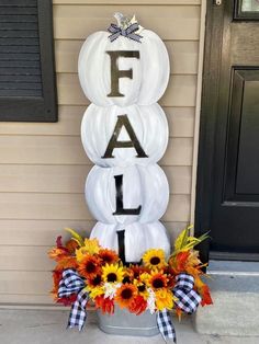 a white pumpkin with the word fall painted on it sitting in front of a house