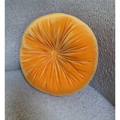 an orange round cushion sitting on top of a gray couch