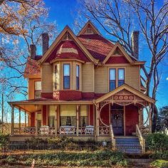 an old victorian style house with red shingles on the front and side porchs