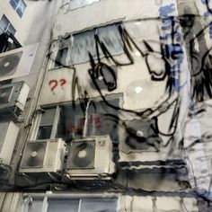 the reflection of an apartment building with graffiti on it's walls and air conditioning units