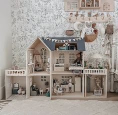 a doll house is shown in front of a wall with many pictures and toys on it