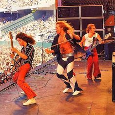 the group of men are playing guitar on stage in front of an arena full of people