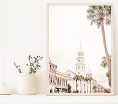 a framed photograph of a palm tree in front of a white building with a clock tower