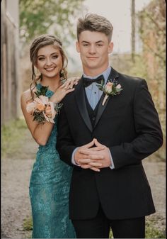 a man in a tuxedo standing next to a woman wearing a blue dress